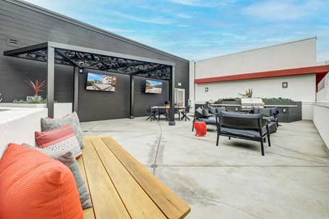 A patio with a wooden table and chairs under a black awning.